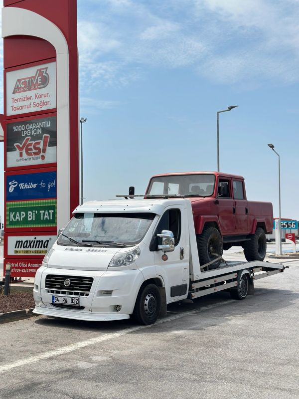 Siyah beyaz kurtarıcı kamyonet kırmızı arazi aracını taşıyor.