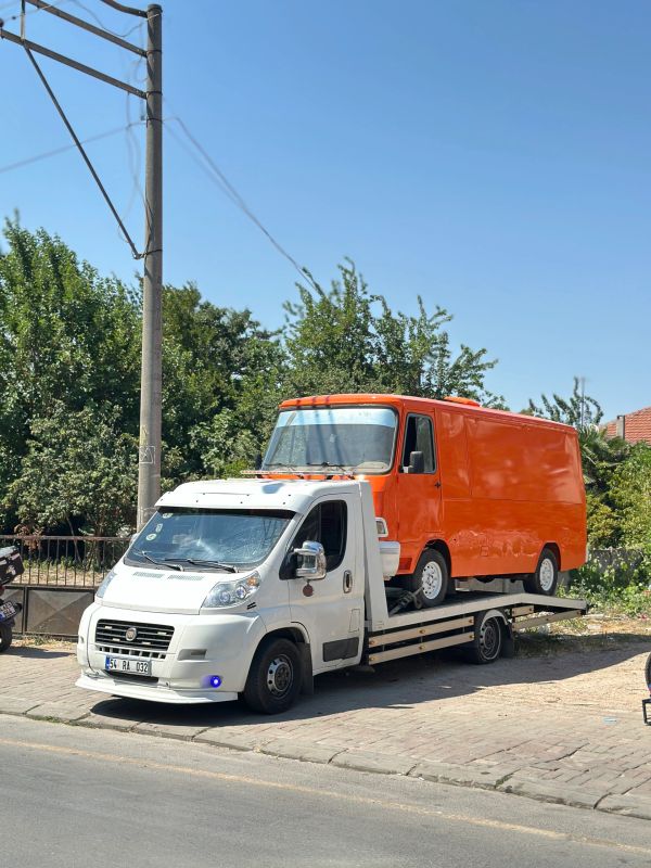 Beyaz çekici üzerinde turuncu bir kamyonet var.