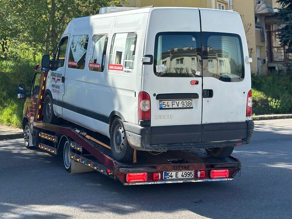 White van being towed on a flatbed truck.