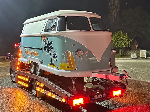 Vintage camper van on a flatbed truck at night.