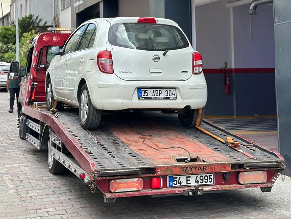 A white Nissan Micra on a tow truck.