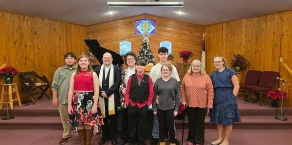 Group photo of nine people in a church with Christmas decorations.