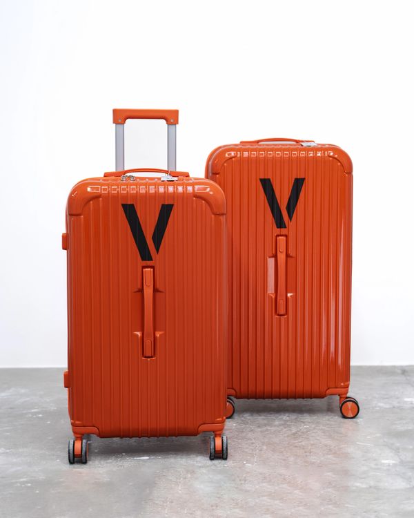 Two orange suitcases with black V logo.