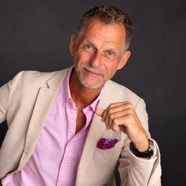 Confident middle-aged man in beige blazer and pink shirt.