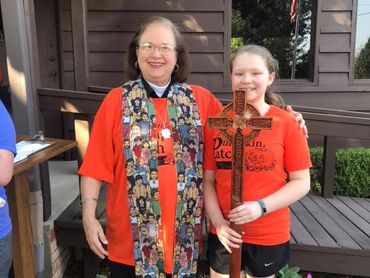 Female Episcopal priest and young parishioner with Christian cross.