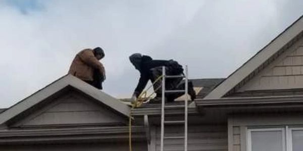 Professional roofing contractors performing expert roof repairs and siding inspection on a residenti