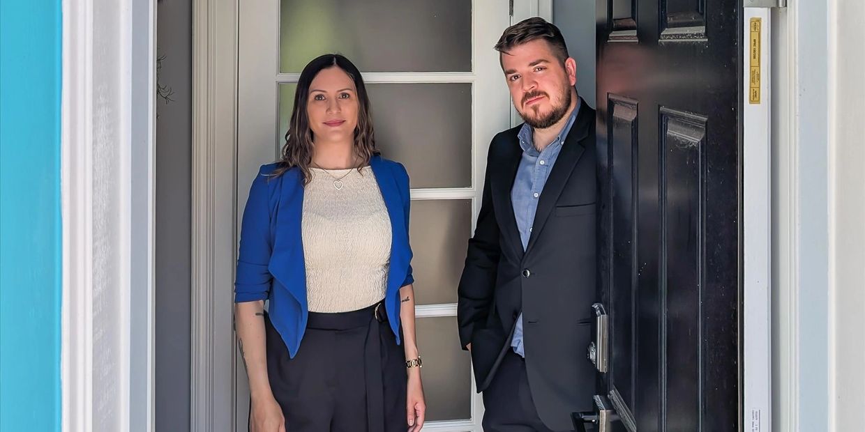 Two real estate agents standing inside the doorway of a home they're listing for sale in St. John's.