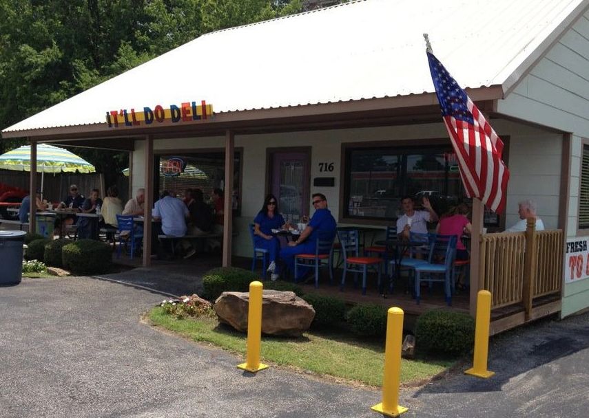 People dining outside a deli with an American flag.