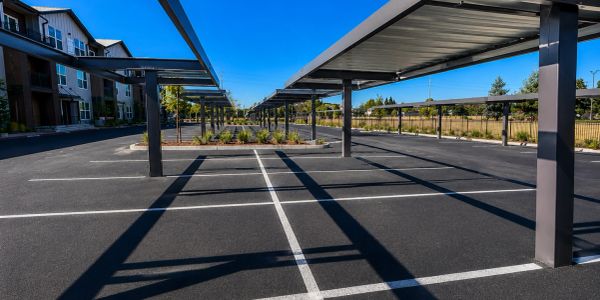 Empty parking lot with covered spaces under a clear blue sky.