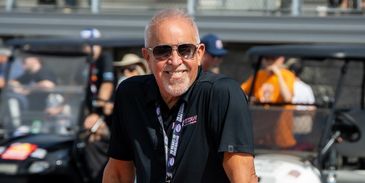 Smiling man wearing sunglasses at an outdoor event.