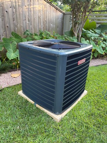 Outdoor Goodman air conditioning unit on grass.