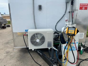Air conditioning unit connected to a propane tank with gauges.