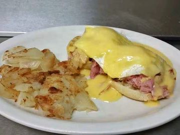 Eggs Benedict with hash browns on a plate.