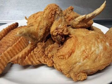 Fried chicken wings and potato fries on a white plate.