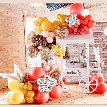 Colorful balloon arch and cart setup for a wild-themed party.
