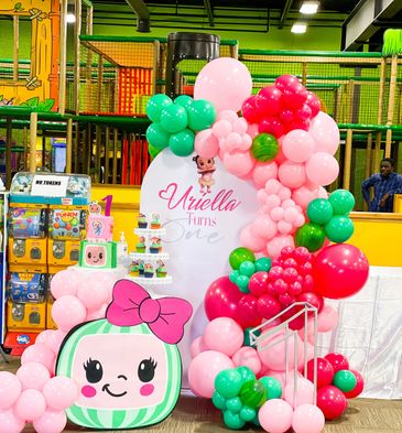 Colorful first birthday party setup with balloons and cake.
