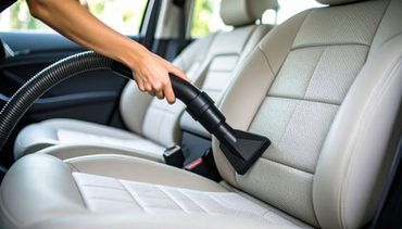 Vacuuming the interior of a car's leather seat.