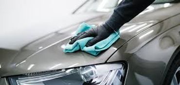 Person cleaning a car hood with a microfiber cloth.