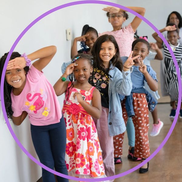 A joyful group of children posing with playful hand gestures indoors.
