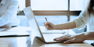 Image of person at a laptop with pen and paper