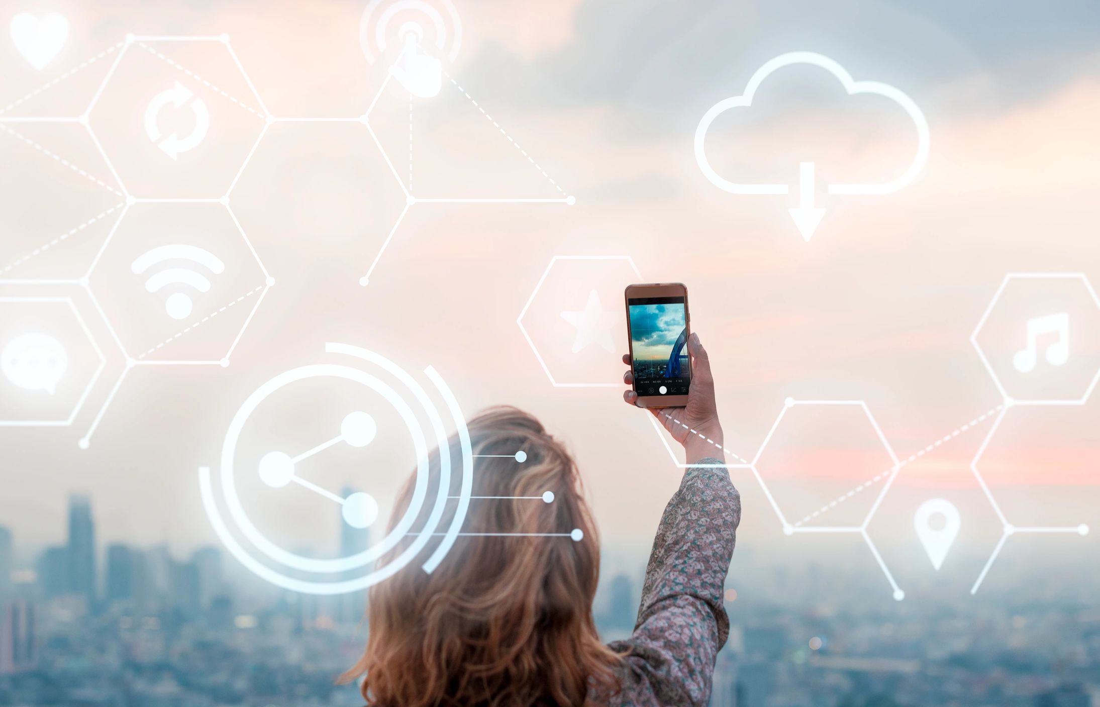 Image of woman holding up a cell phone overlooking a city