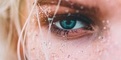 Close-up of a blue eye with water droplets on the face.