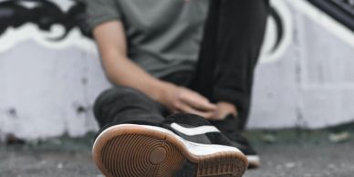 Person sitting on the ground wearing black sneakers.