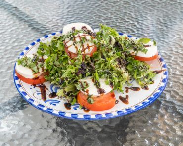 Caprese salad with tomato, mozzarella, basil, and balsamic drizzle.