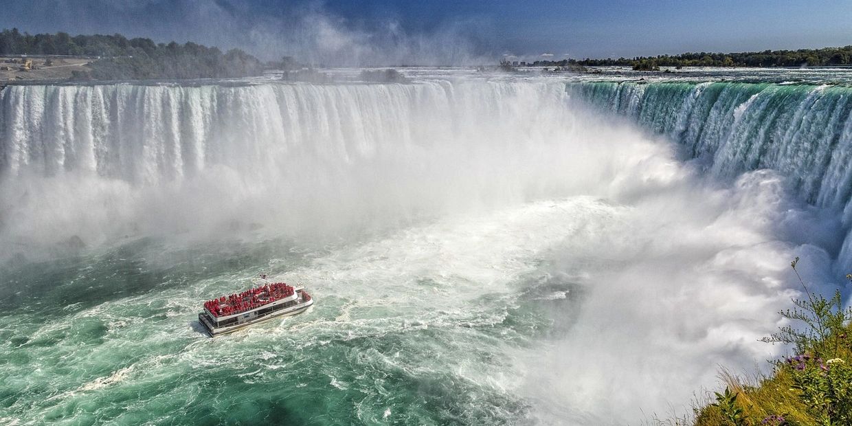 Boat near the base of Niagara Falls surrounded by mist and cascading water.