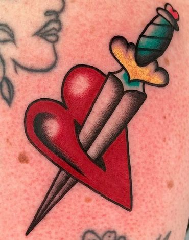 This is a colour tattoo of a heart and dagger in American traditional tattoo style
