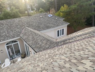 Roof view of a residential house surrounded by trees.