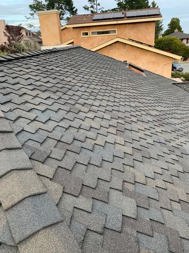 Gray shingled roof with nearby tan house.