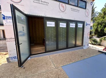 A set of black-framed panoramic doors installed in a building under construction.