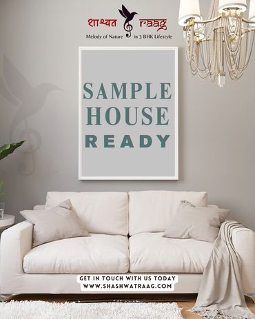 Modern living room with a beige sofa and a framed sign announcing a ready sample house.