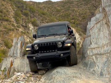 jeep wrangler facing the camera as it drives down a rocky ledge in the Sonoran desert. 