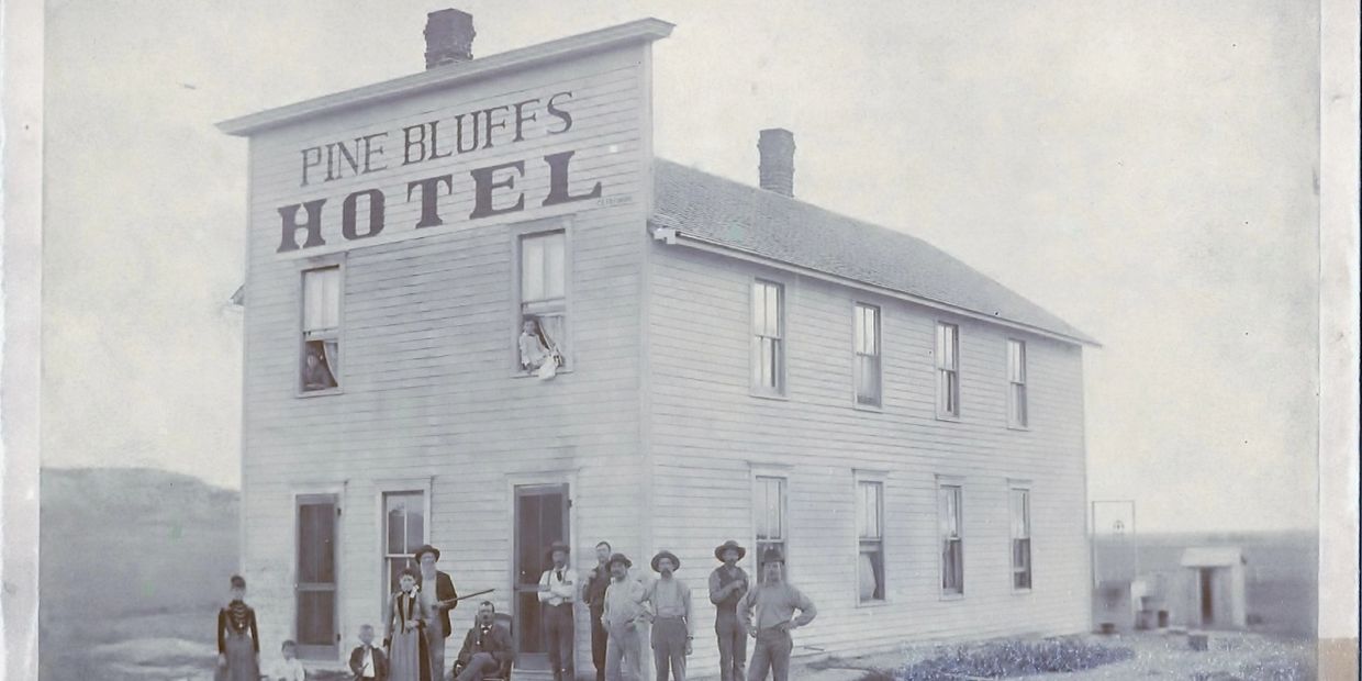 Historic Pine Bluffs Hotel with a group of people posing outside.