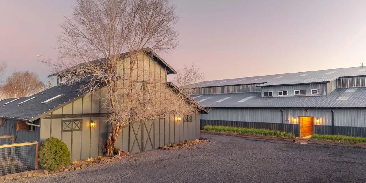 Rustic barn and modern building at dusk with soft lighting.