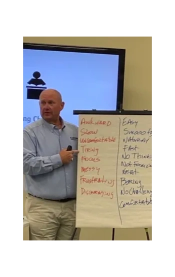 Man pointing at flip chart comparing negative and positive traits in a presentation.