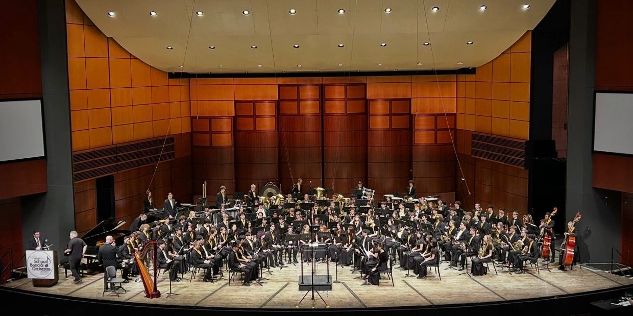 A large orchestra performing on a spacious stage in a concert hall.