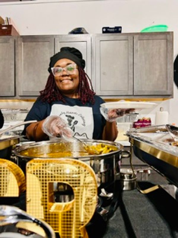 Smiling woman serving food at a buffet with gloves and apron.