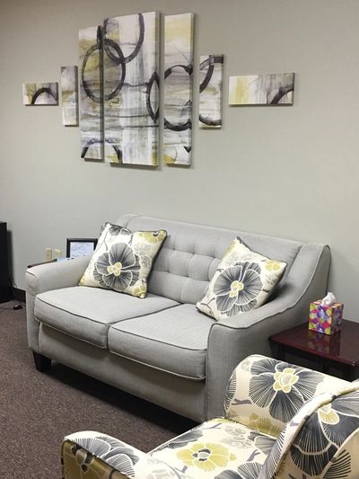 Cozy waiting room with a floral armchair and neutral sofa.