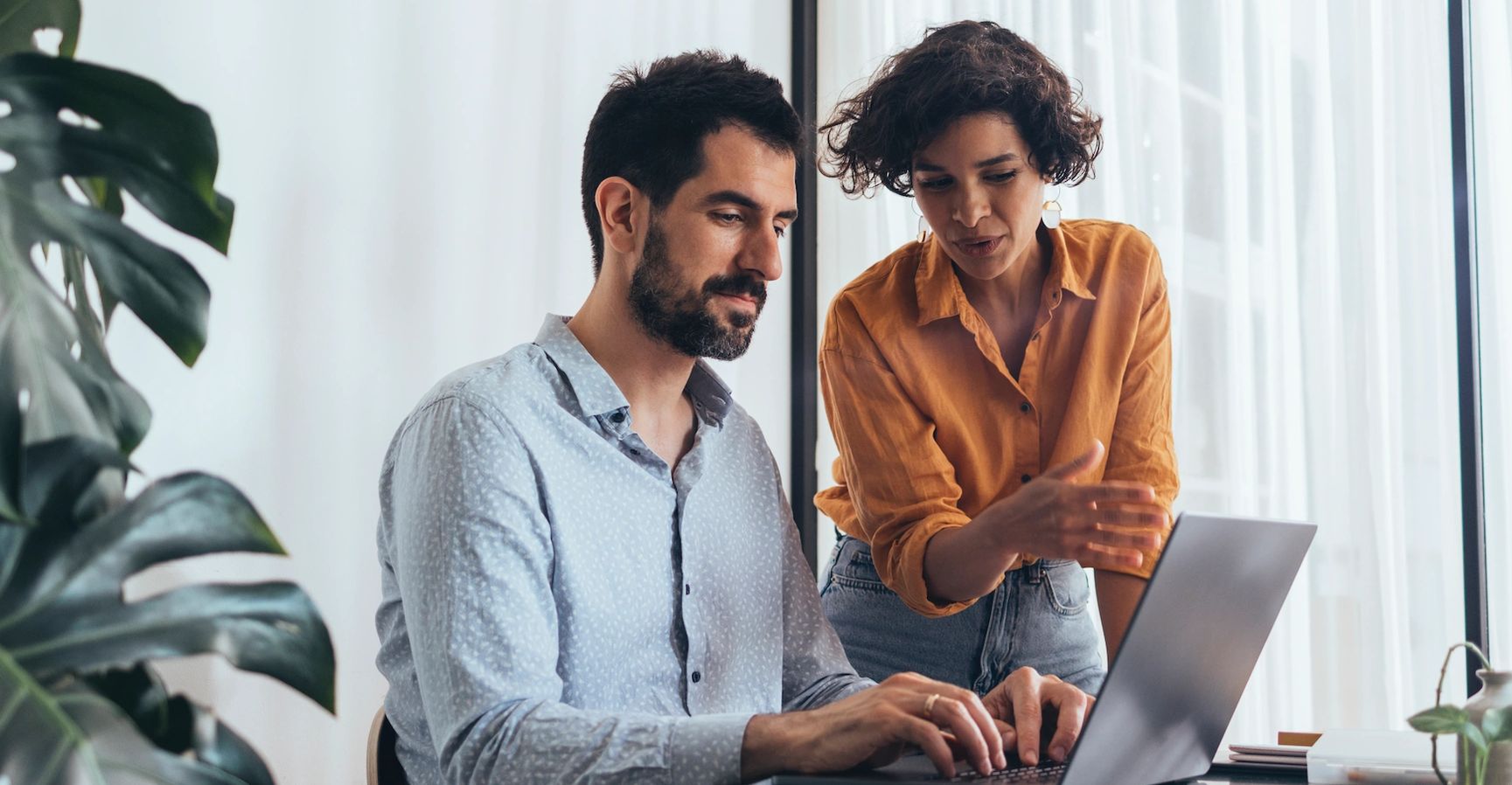 A man with woman discusses Singh and man Working on laptop
