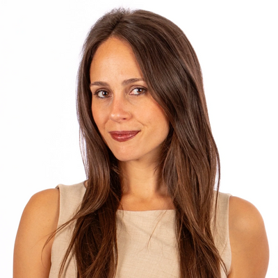 Woman with olive complexion, long brown hair parted in the middle, and brown eyes.