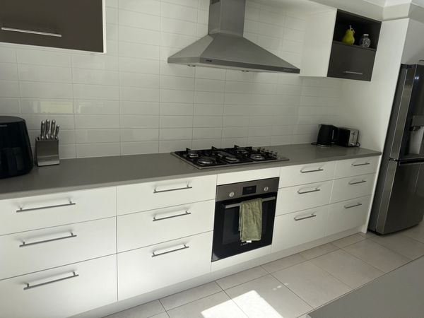 Modern kitchen with white cabinets, stainless steel appliances, and a clean gray countertop.