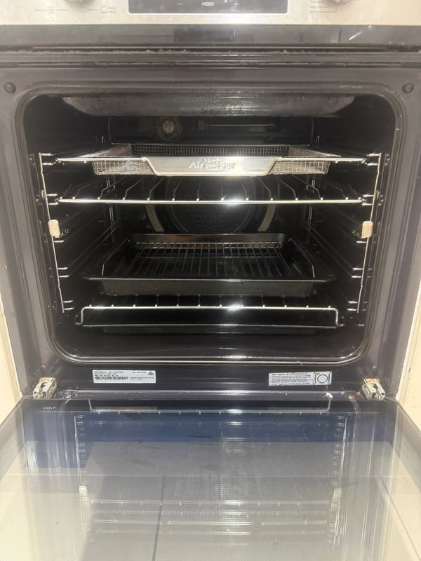 Open oven with multiple racks and trays inside.