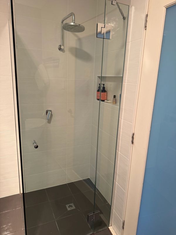 Modern glass shower enclosure with rain showerhead and tiled walls.