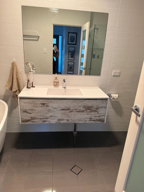 Modern bathroom with a floating rustic vanity and large mirror.