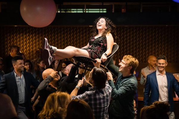 A woman sitting on a chair and a man getting up or down from the chair to touch the woman