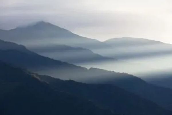 Fog drifting over layered mountain ridges.