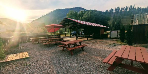 Outdoor picnic area with red umbrellas and tables at sunset.